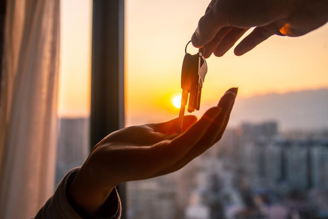 Una persona está entregando las llaves de la casa y se espera que el nuevo propietario pague El Impuesto de Plusvalía